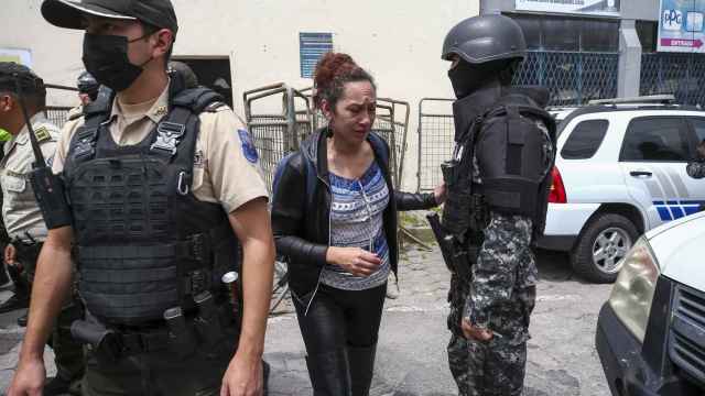 La familiar de un detenido, al lado de un agente de la Policía fuera de la cárcel de El Inca de Quito, este jueves.