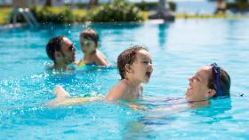 Una familia juega con sus hijos en la piscina.