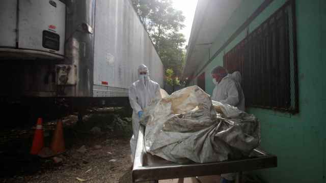 Técnicos forenses descargan un cadáver de un remolque frigorífico en la morgue de Tegucigalpa, este miércoles.