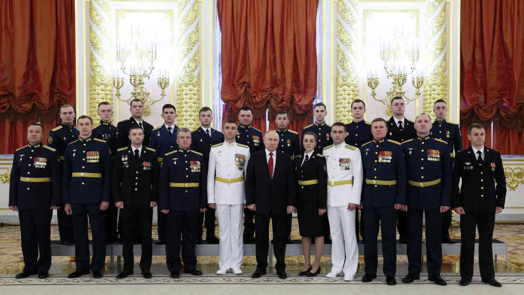 Vladimir Putin poses for a photo with graduates of Russia's military institutions of higher education during a meeting in the Kremlin.