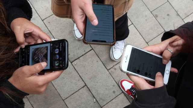 Varios jóvenes usando sus teléfonos móviles.