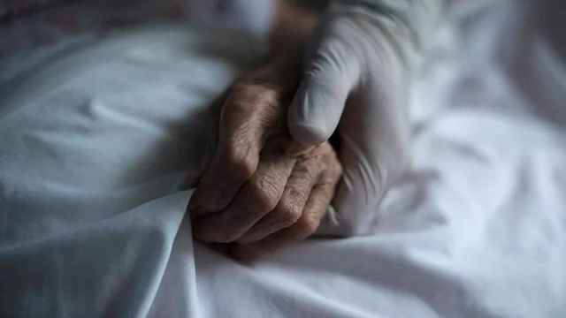 Una sanitaria coge la mano de una persona mayor, en imagen de archivo.