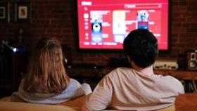 Una pareja viendo la televisión en su domicilio.