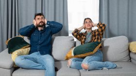 Una pareja joven se tapa los oídos porque les molesta el ruido de los vecinos.