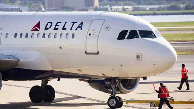 Un avión de la empresa Delta controlado por operarios en la pista de aterrizaje