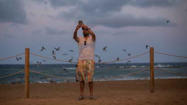 Un hombre se hace una foto en una playa de Barcelona.
