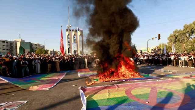 Banderas LGBTI profanadas en Bagdad: una en llamas, otras con señales de prohibición dibujadas.