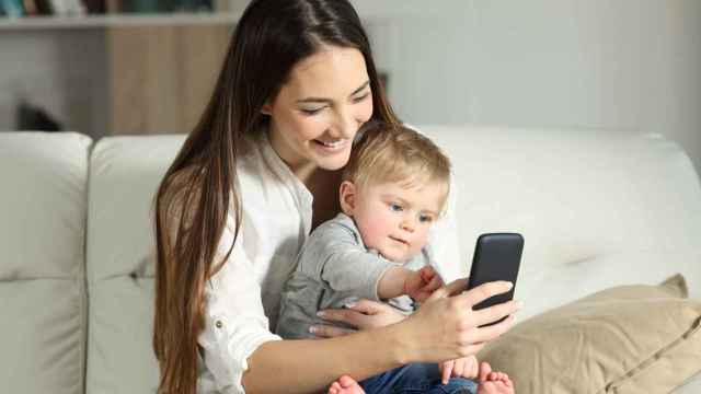 Una mujer con su bebé y el móvil.