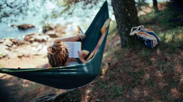 Una mujer leyendo un libro en una hamaca.