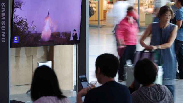 Los pasajeros esperan su tren frente a un televisor que transmite un informe de noticias sobre Corea del Norte disparando un misil balístico frente a su costa este, en una estación de tren en Seúl, Corea del Sur.