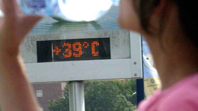 Un hombre pasea por una calle de Valladolid delante de un termóemtro que marca 39 grados.