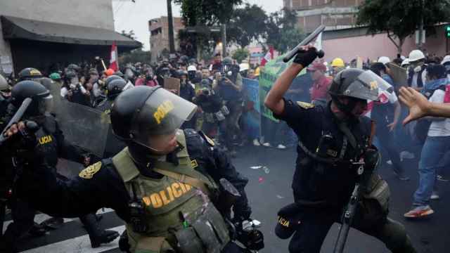 Policías antidisturbios cargan contra los manifestantes antigubernamentales, en Lima.