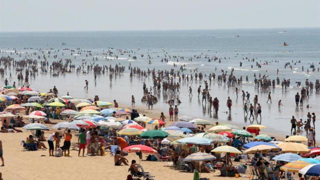 Imagen de una playa repleta de sombrillas.