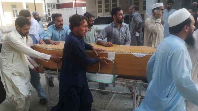 Varias personas mueven ataúdes fuera de un hospital tras el atentado, Pakistán.