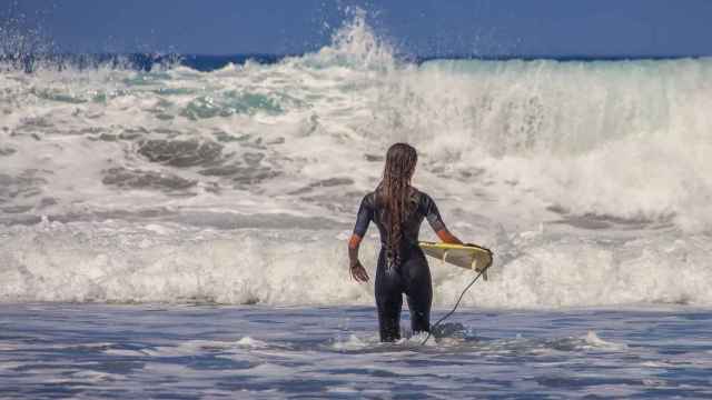 Una surfista se dispone a meterse en el mar para practicar este deporte.