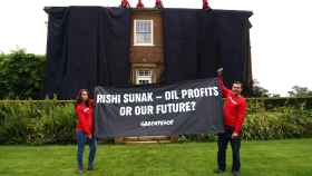 Activistas de Greenpeace sosteniendo una pancarta en modo de protesta frente a la casa del primer ministro británico.