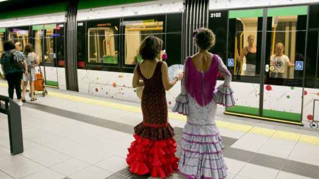 Dos mujeres vestidas de gitana, en el interior de una de las estaciones del Metro de Málaga.
