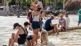 Un grupo de turistas se refresca en una fuente por las altas temperaturas.