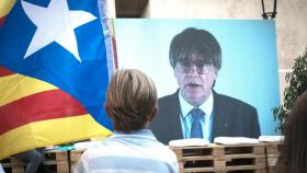 Un niño observa la intervención telemática de Puigdemont en un mitin de JxCAT en Girona, el pasado julio