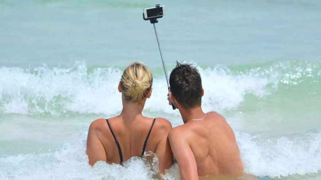 Dos personas haciéndose un selfie frente a una ola