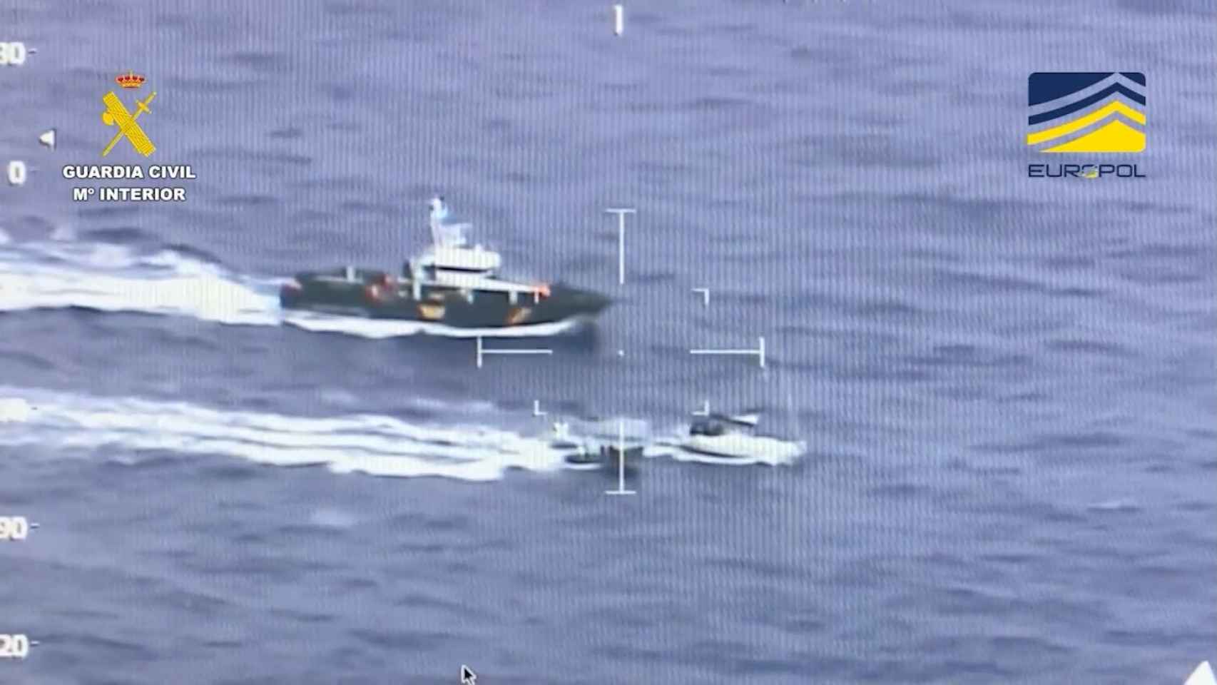 El velero rodeado por embarcaciones de la Guardia Civil y observado por un helicóptero.