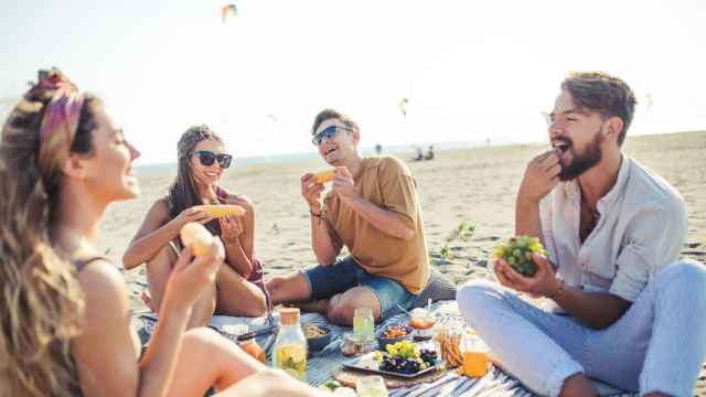 Un grupo de amigos disfruta comiendo en la playa.
