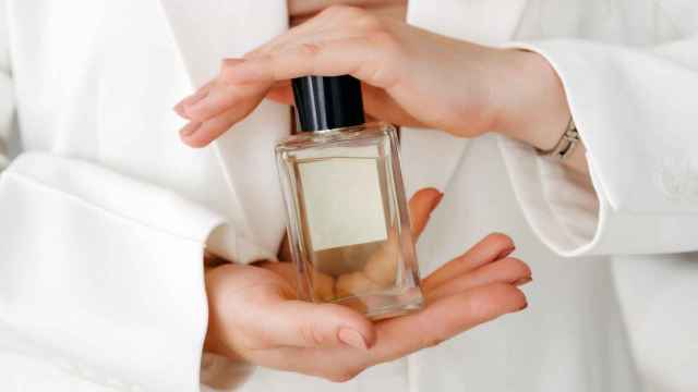 Una mujer, sujetando un perfume.