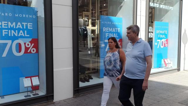 Dos personas pasan junto al escaparate de un establecimiento que anuncia rebajas del 70% en su interior