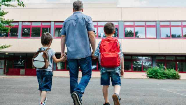 Un padre acompaña a su hijos al colegio.