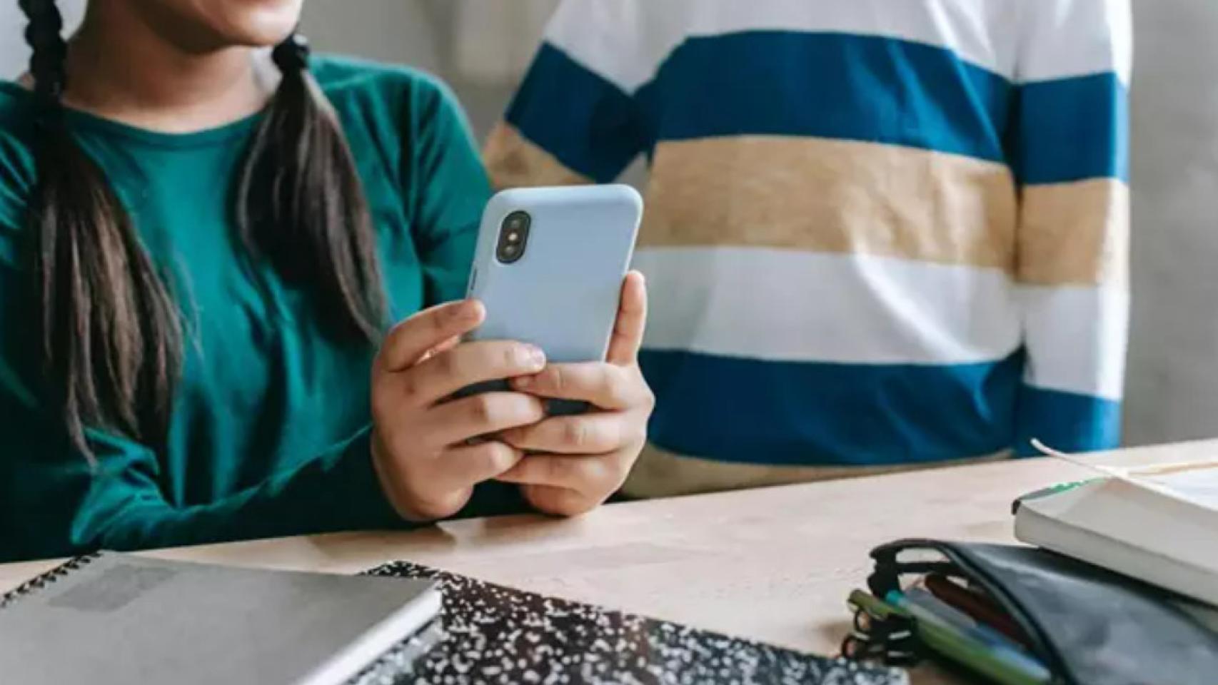 Unos menores de edad utilizando un teléfono móvil.