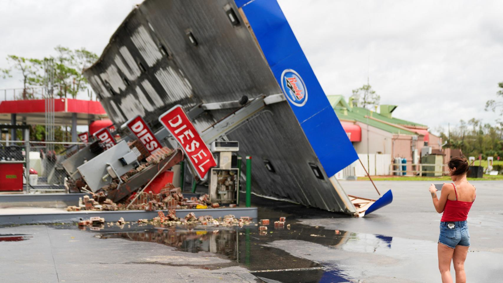 Una mujer observa una gasolinera destrozada tras el paso de Idalia por Florida.