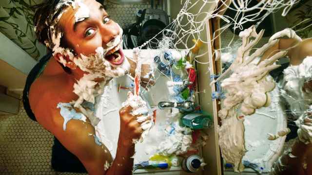Hombre que juega en el baño con pasta de dientes y crema de afeitar. Foto: iStock.