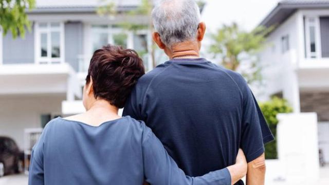 Dos jubilados abrazados frente a su casa