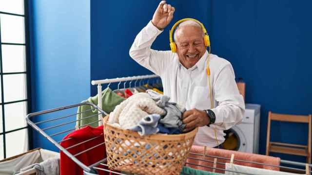 Hombre escuchando música colgando ropa en el tendedero. Foto: iStock.