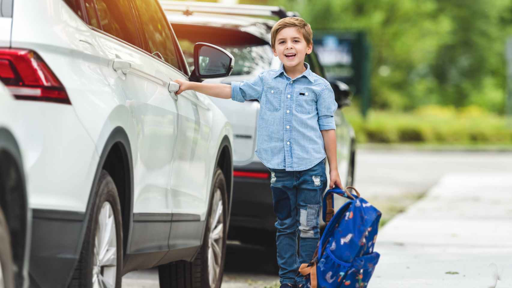 Un niño con una mochila escolar a punto de abrir la puerta del coche.