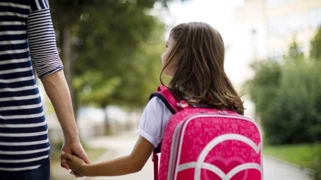 Una madre y su hija con mochila escolar acuden al colegio.