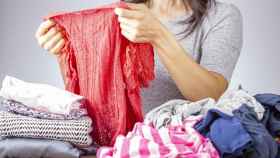 Imagen de archivo de una mujer doblando prendas de ropa.