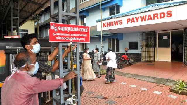 Operarios instalan un cartel designando el bloque de aislamiento por nipah en un hospital de Kozhikode.