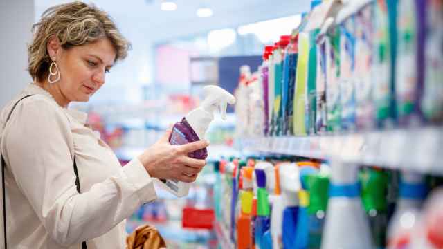 Una mujer mira la etiqueta de un producto de limpieza en un supermercado.