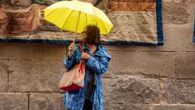 Un mujer se protege de la lluvia en las calles de Toledo.