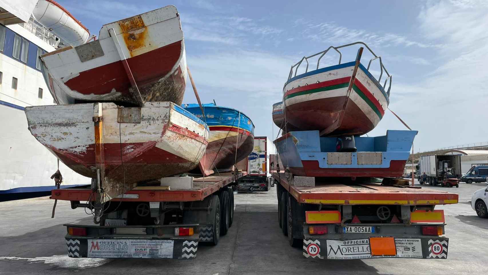 Camiones cargan en los ferries las barcas con las que han llegado los migrantes a Lampedusa.