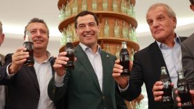 El presidente de la Junta de Andalucía Juanma Moreno (c), el alcalde de la Rinconada Javier Fernández (i), y el director general de CCEP Iberia, Francesc Cosano (d), brindan por el 25 aniversario de la planta de Coca Cola en la Rinconada, Sevilla.