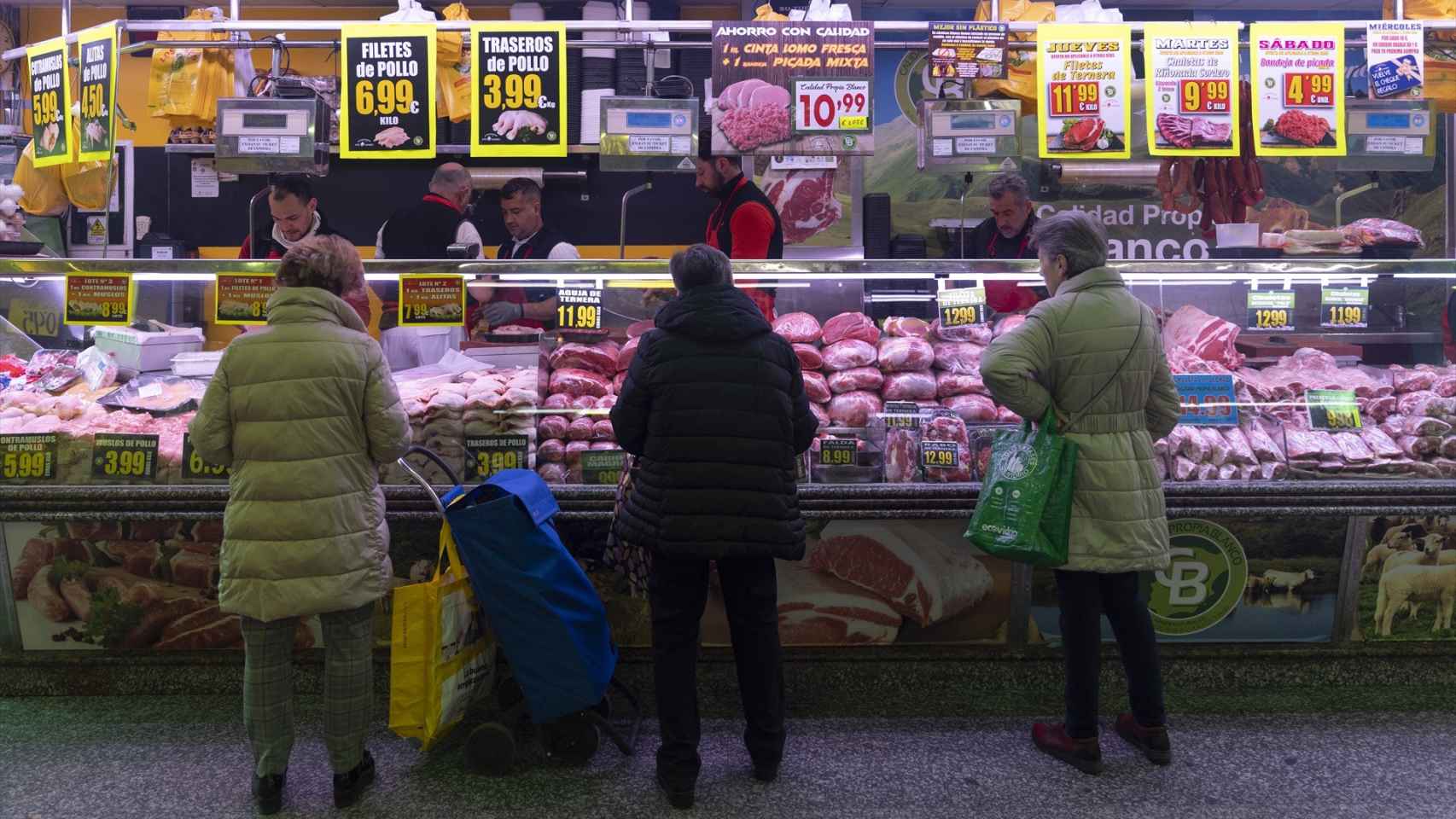 Varias mujeres compran en una carnicería en un mercado.