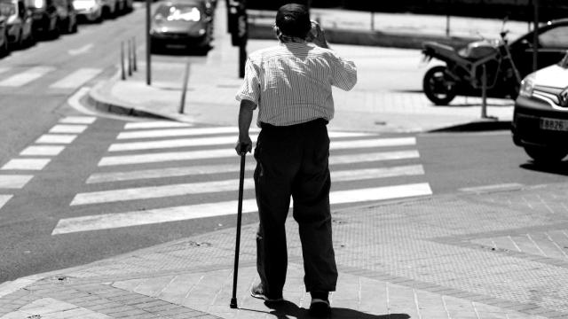 Un hombre mayor pasea apoyándose en un bastón en Madrid.