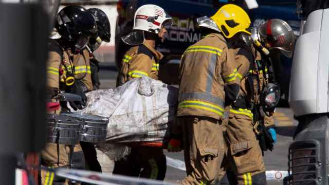 Los bomberos trasladan el cadáver de uno de los 13 fallecidos en el interior de 'La Fonda Milagros'