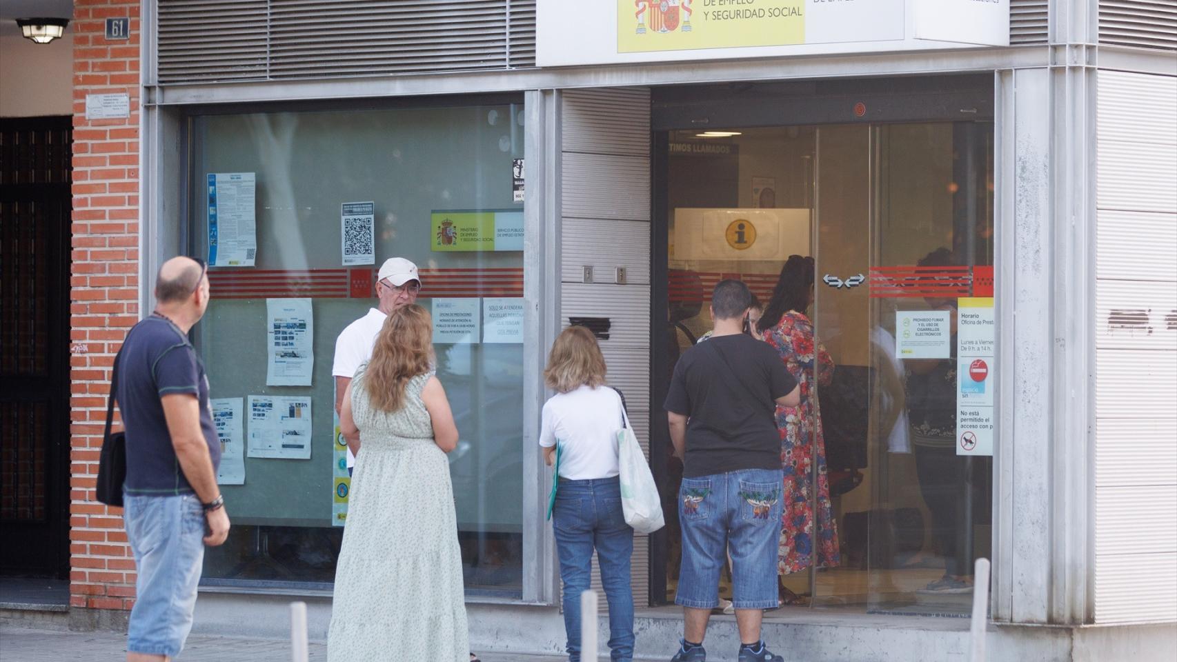 Varias personas delante de una oficina de empleo.