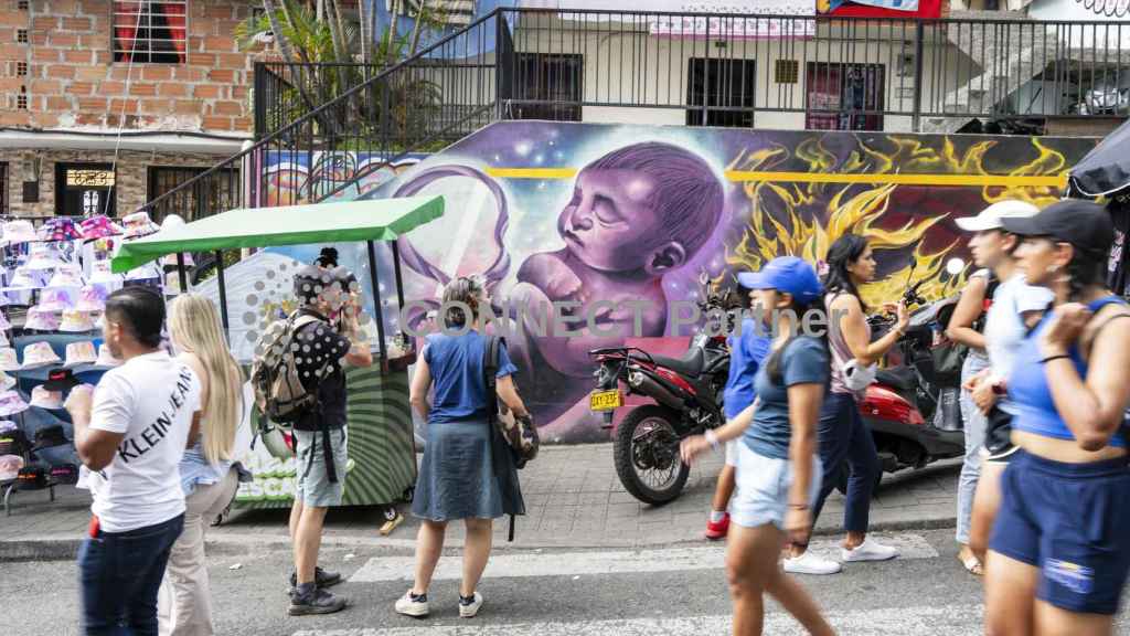 Visitantes pasean junto a un mural en la Comuna 13 de Medellín, Colombia.