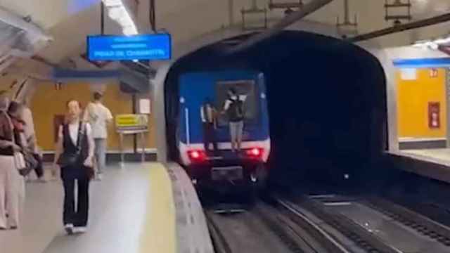 Dos jóvenes subidos a un vagón de metro en marcha