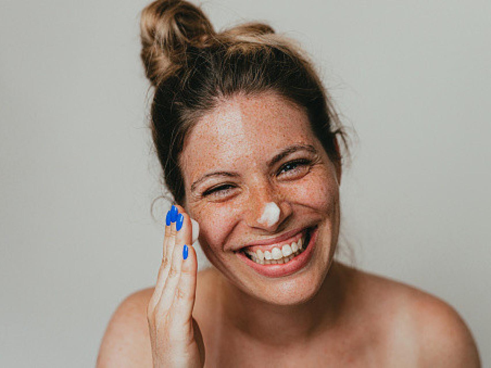 Una mujer aplicando crema hidratante