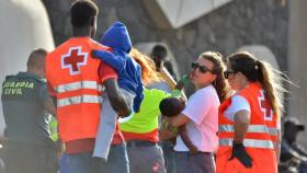 Voluntarios de la Cruz Roja reciben a migrantes al pisar tierra en la isla canaria de El Hierro.